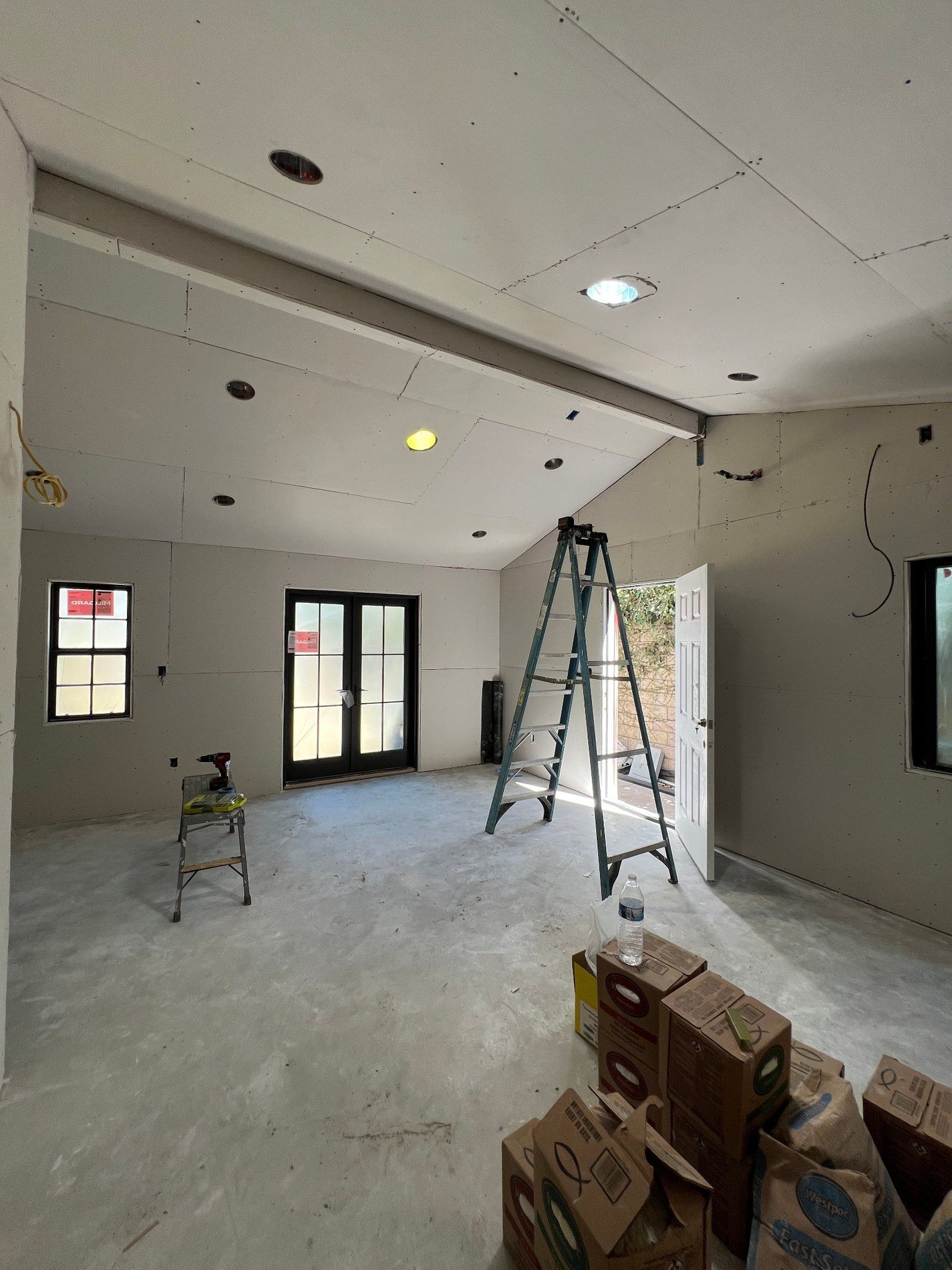 ADU interior after drywall installation with recessed light openings and French doors