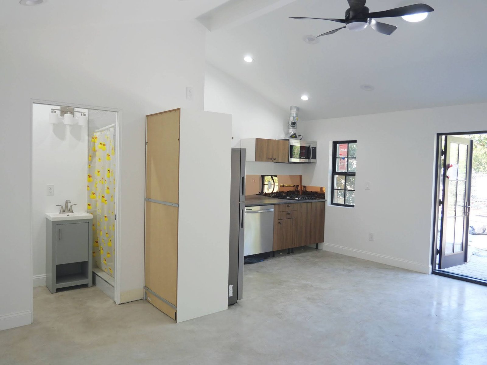 Completed ADU interior with kitchenette, bathroom entrance, recessed lighting, and ceiling fan