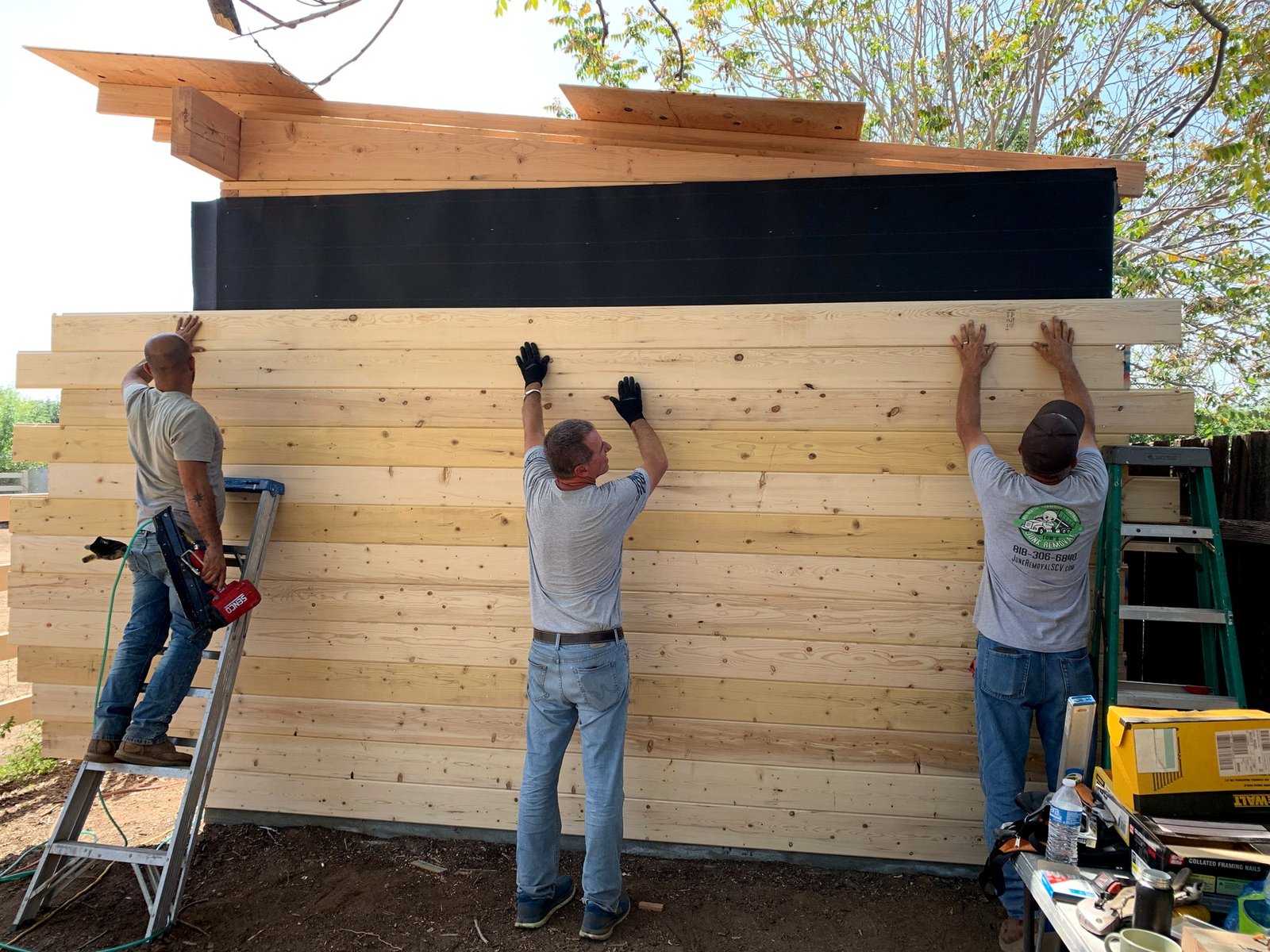 Crew installing horizontal wood siding on the custom barn